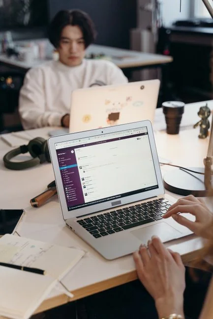 A modern workspace showing hands analyzing marketing data on a laptop and paper documents.